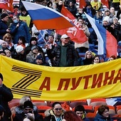 Demonstracja wsparcia dla wojny na Ukrainie.Stadion Łużniki, Moskwa, 18 marca 2022 r.  Na transparencie wykorzystany został znak „Z” – symbol agresji – rozwinięty w hasło: „Za Putina”. Literę „Z” tworzy tzw. wstążka św. Jerzego, symbolizująca zwycięstwo nad III Rzeszą.