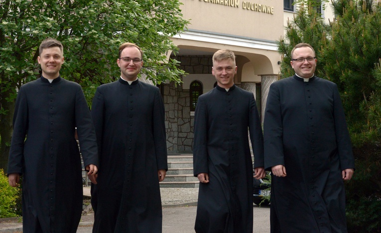 Kandydaci do święceń przed frontonem Wyższego Seminarium Duchownego. Idą od lewej w porządku alfabetycznym.