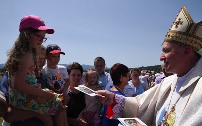 Bp Andrzej Jeż rozdaje modlitewniki rodzinne.