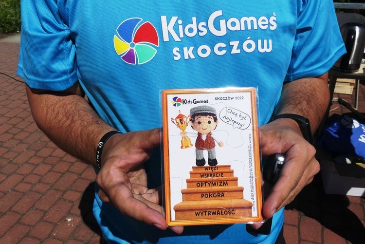 Ks. Przemek Guzior prezentuje magnes na lodówkę - pamiątkę 5. Igrzysk Kids Games w Skoczowie.