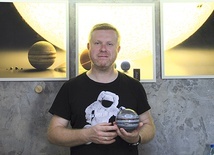 Współtwórca AstroLabu z modelem Jowisza. Za nim grafika ukazująca wielkość Słońca i planet.