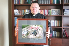	Ksiądz Dariusz Tkaczyk pokazuje zdjęcie kościoła z czasu budowy.