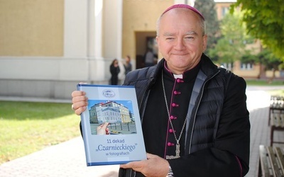 Bp Jan Sobiło z albumem pokazującym historię jego liceum.