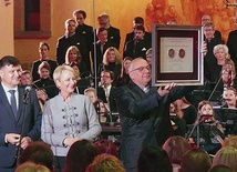 Ks. Fryderyk Tarabuła prezentuje medal Polonia Minor. Obok  –  Iwona Gibas i Rafał Kosowski.