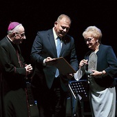 ▼	Bp Jacek Jezierski i Michał Missan, wiceprezydent Elbląga, wręczają Elżbiecie Szandrosze statuetkę i kwiaty.