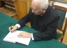 Biskup Andrzej F. Dziuba podpisuje jubileuszową książkę.