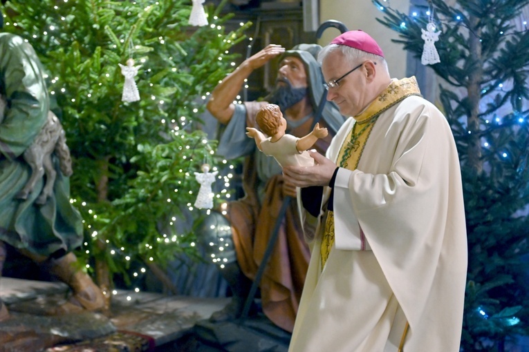 Biskup wnoszący figurkę Dzieciątka Jezus do katedralnej szopki.
