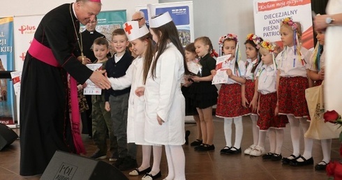 Nagrodę zespołowi Patriotyczne Zajączki wręcza bp Marek Solarczyk.