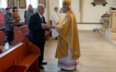 Biskup składający odchodzącemu na emeryturę kościelnemu gratulacje.