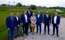 Uczestnicy konferencji na tle terenów w pobliżu linii kolejowej, na których zostanie zbudowana nowa nitka trasy z południa na północ Radomia.