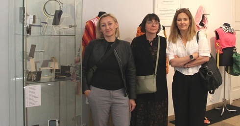 Na tle wystawy z prof. UTH Hanną Wojdałą-Markowską (w środku) Marta Orzechowska-Ochnia (z lewej) i Aleksandra Kwiecień, doktorantki Uniwersytetu Technologiczno-Humanistycznego w Radomiu.