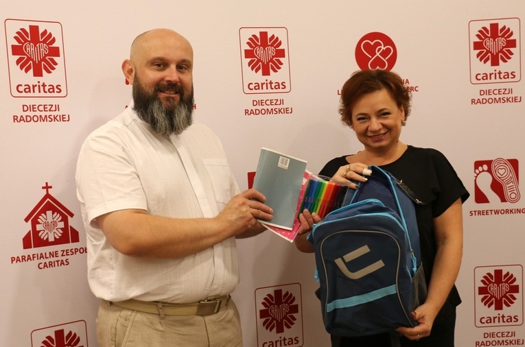 Ks. Damian Drabikowski i Iwona Stępniewska zachęcają do przekazywania przyborów szkolnych.