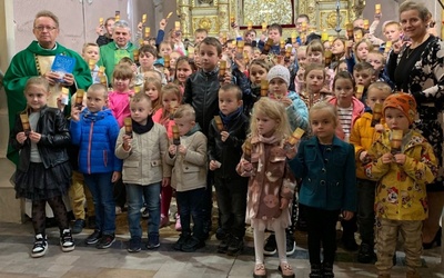 Dzieci pokazują zakładki do Pisma Święta. Na zdjęciu z ks. Jackiem Kucharskim i ks. Mirosławem Jakubiakiem.