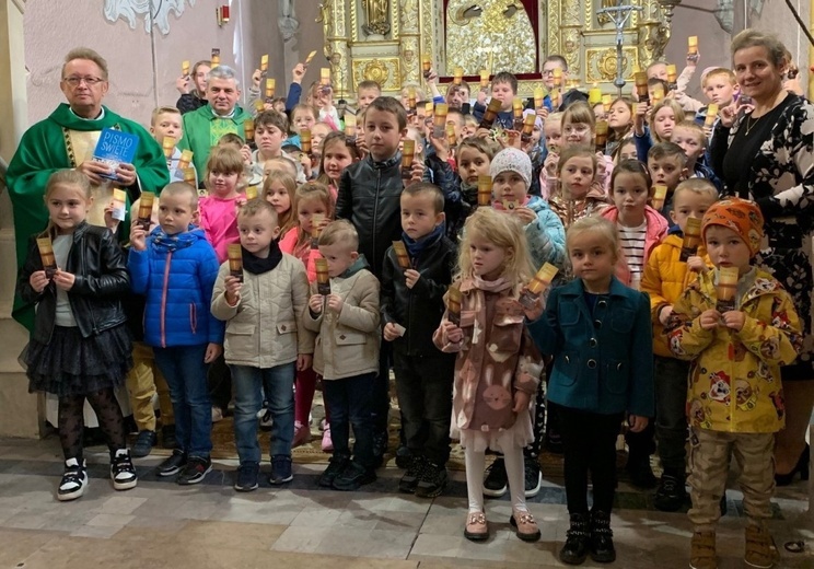 Dzieci pokazują zakładki do Pisma Święta. Na zdjęciu z ks. Jackiem Kucharskim i ks. Mirosławem Jakubiakiem.