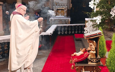 Biskup okadza figurkę Dzieciątka Jezus.