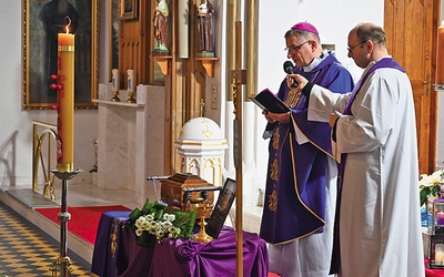 ▲	Biskup modli się  nad urną z prochami zmarłego.