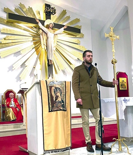 Neokatechumeni stają przed zgromadzeniem i opierając się o krzyż, świadczą o Bogu.