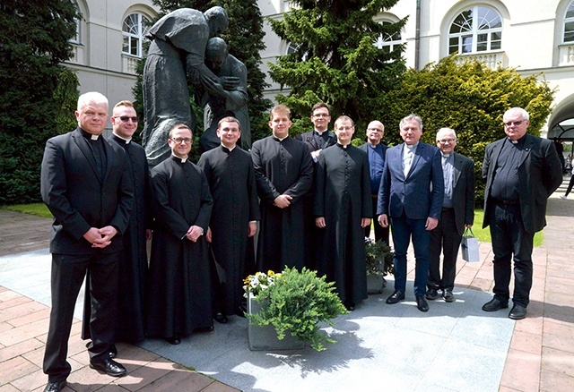 Świeżo upieczeni magistrzy przy pomniku św. Jana Pawła II  i bł. kard. Stefana Wyszyńskiego  na dziedzińcu uczelni.