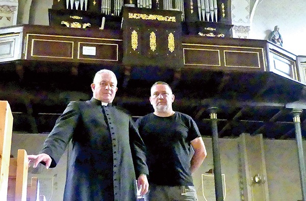 Tutejszy proboszcz i Tadeusz Kalfas pod wyremontowaną balustradą chóru.