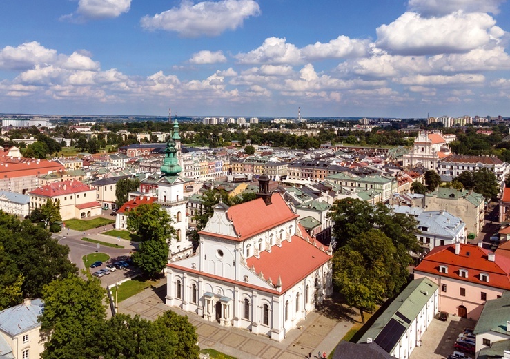 Zamość z lotu ptaka. Na pierwszym planie kolegiata. W tle skąpane w słońcu ulice przecinające się pod kątem prostym.