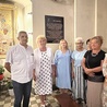 Grupa dawnych uczniów na tle tablicy upamiętniającej nauczycielkę katechezy w oświęcimskim kościele Wniebowzięcia NMP.