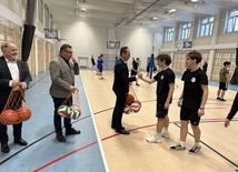 Poseł Rafał Weber przekazuje uczniom piłki.
