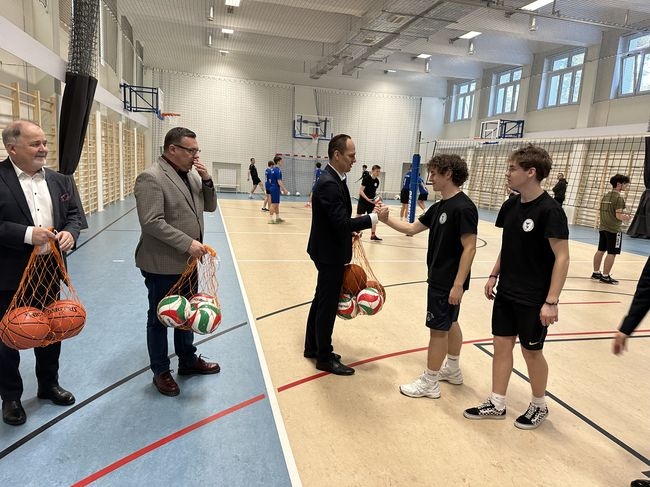 Poseł Rafał Weber przekazuje uczniom piłki.