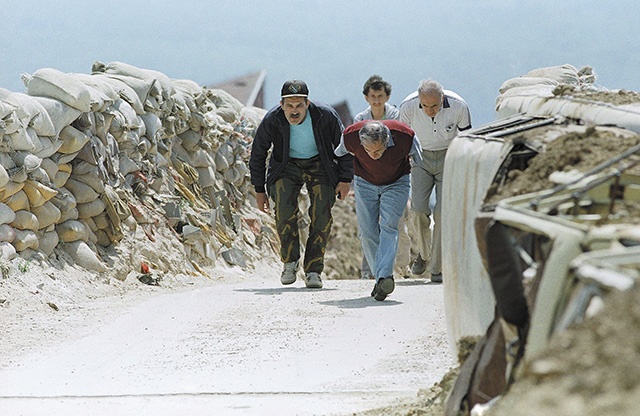 Czerwiec 1993 r. Mężczyźni przebiegają przez most na przedmieściach Sarajewa. Worki z piaskiem miały chronić ludność przed kulami snajperów nieustannie ostrzeliwujących miasto. 