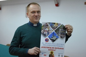 Ks. Krzysztof Bochniak prezentuje plakat pielgrzymki na Jasną Górę.