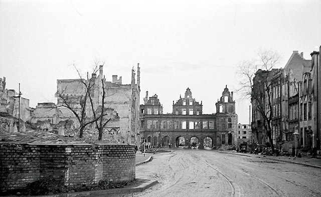 	Rok 1945. Ruiny Długiego Targu. W tle spalona Brama Zielona, z lewej strony na pierwszym planie ceglana obudowa podstawy Fontanny Neptuna.