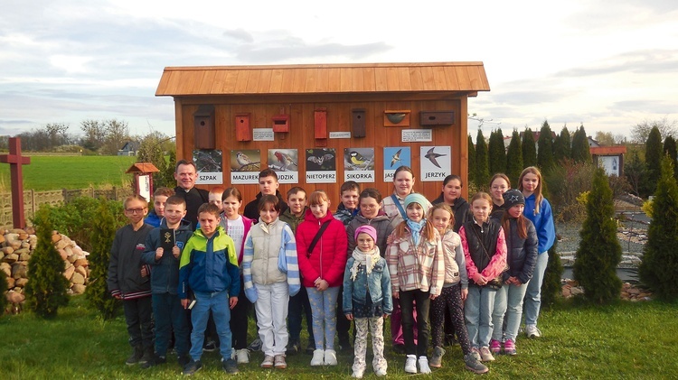 Ks. Rafał Wyleżoł  z grupą dzieci przy budkach lęgowych. 