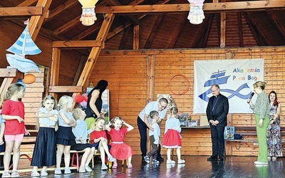 Dzieci wręczają biskupowi laurkę w podziękowaniu za odwiedziny.
