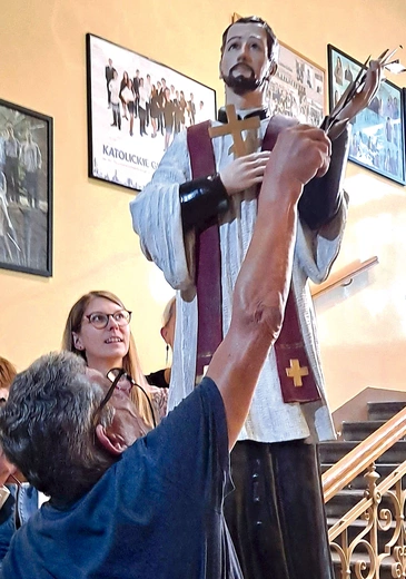 „Groźny woźny” poprawia liść palmy, który od lat „kusi” licealistów do wyjmowania go z ręki świętego.