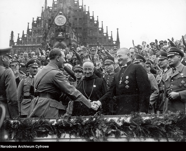 Adolf Hitler na wiecu NSDAP 6 września 1934 r. w Norymberdze wita wspierających nazizm duchownych. To ewangelicki biskup Ludwig Müller oraz benedyktyński opat Albanus Schachleitner (w okularach), na którego Kościół katolicki nałożył karę suspensy (zawieszenia w czynnościach kapłańskich).