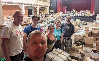 	Duszpasterz Maciejówki wraz z innymi osobami przy sortowaniu darów.