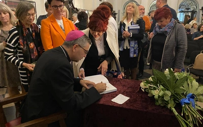 Podczas spotkania bp W. Osial podpisywał swoją publikację.