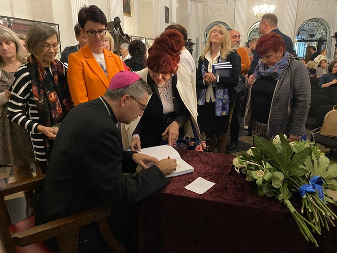 Podczas spotkania bp W. Osial podpisywał swoją publikację.