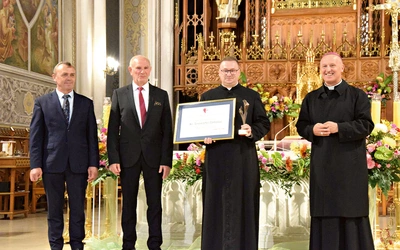 Ks. Tomasz Pastuszka, nagrodzony duszpasterz, ze statuetką i dyplomem.