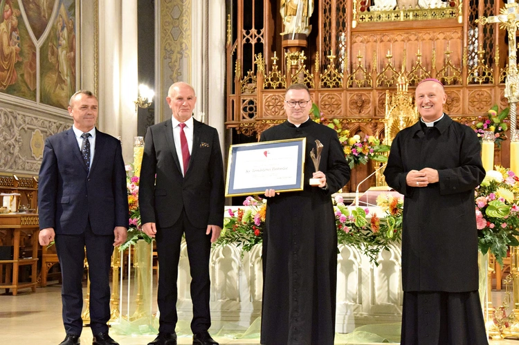 Ks. Tomasz Pastuszka, nagrodzony duszpasterz, ze statuetką i dyplomem.
