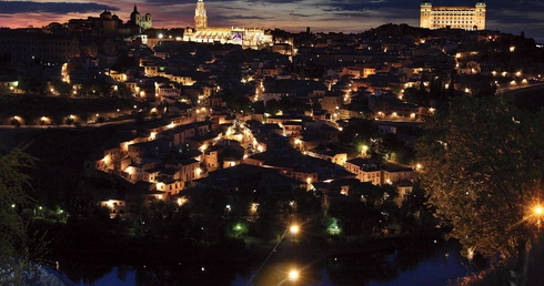Panorama Toledo.  Ta dawna stolica  państwa Wizygotów  i późniejsza stolica Królestwa Hiszpanii została odzyskana  przez chrześcijan w 1085 roku. Dwa najbardziej oświetlone obiekty to gotycka katedra (w środku)  i alkazar (z prawej)  – dawna twierdza,  obecnie Muzeum Wojska.