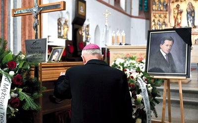 Biskup modli się przy trumnie zmarłego.