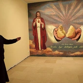 Ks. Artur Fura prezentuje mozaikę z Jezusem i Maryją.