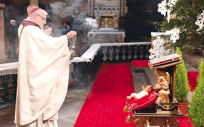 Bp Marek Mendyk okadza figurkę Dzieciątka.