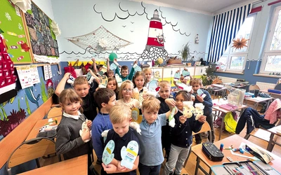 Najmłodsi uczą się w bajecznie kolorowych klasach. Na zdjęciu z dumą prezentują samodzielnie wykonane rękawiczki z kolorowego papieru i waty.