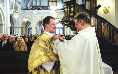 W nałożeniu szat diakońskich pomaga Karolowi Skurze proboszcz parafii.