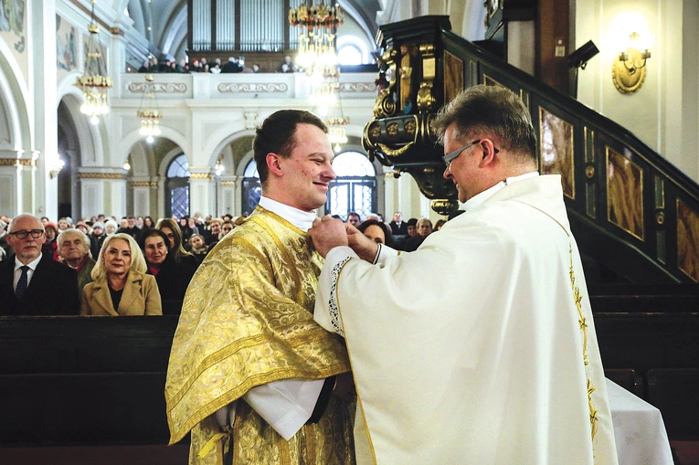 W nałożeniu szat diakońskich pomaga Karolowi Skurze proboszcz parafii.