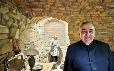 W anturażu kamienno-ceglanych ścian stoi we wnęce św. Jan Vianney.