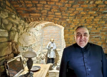 W anturażu kamienno-ceglanych ścian stoi we wnęce św. Jan Vianney.