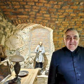 W anturażu kamienno-ceglanych ścian stoi we wnęce św. Jan Vianney.