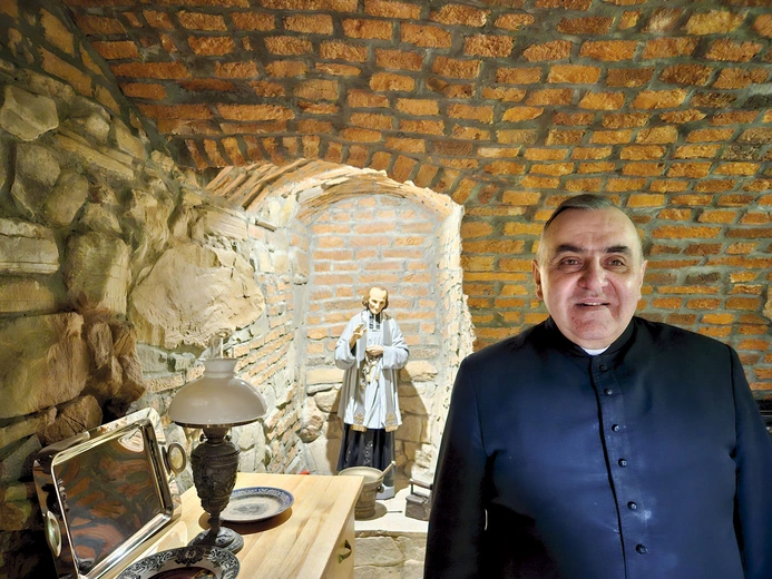 W anturażu kamienno-ceglanych ścian stoi we wnęce św. Jan Vianney.